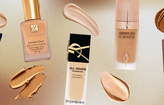 5 different foundations of different shades with swatches on a background of brown and beige gradient