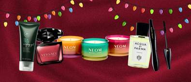 beauty products on a burgundy background with multi-coloured string lights on the top border