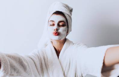 woman taking a selfie with face mask on and dressing gown and towel
